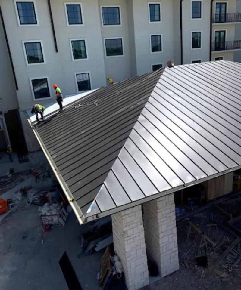 Crew installing standing seam metal roof panels on a commercial project in Patton
